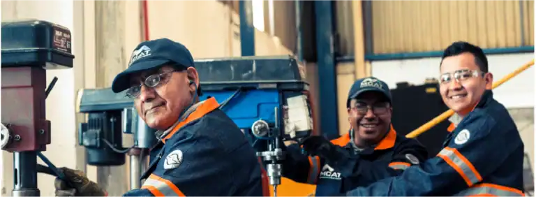 Técnicos de MCAT en taller con equipo de perforado y EPP — fabricación e instalación de ventilación industrial