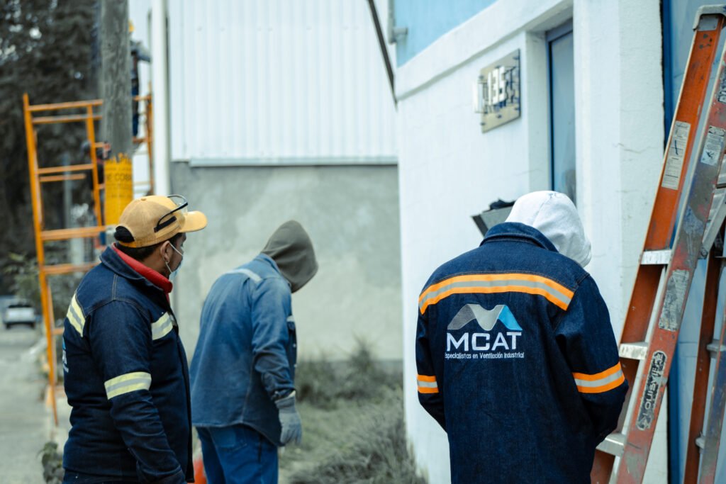 Técnicos de MCAT realizando instalación y mantenimiento de ventilación industrial en sitio; revisión de equipos y seguridad en planta
