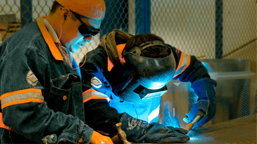 Técnicos realizando soldadura en taller metalmecánico; fabricación de ductería y componentes para ventilación industrial con control de calidad