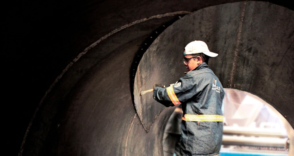Técnico realizando inspección y medición en ducto industrial de gran diámetro; fabricación de ductería y ventilación industrial con control de calidad